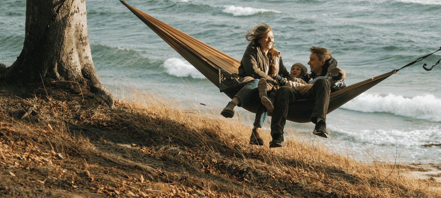 En familie på tre hygger i en hængekøje lige ud til havet på Fyn i Nyborg.