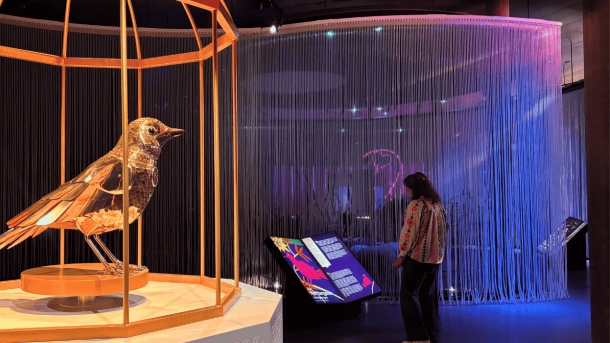 En kvinde står på en farverig udstilling og læser en lysende overdimensioneret bog