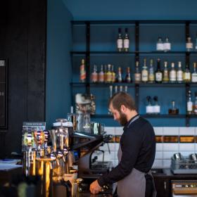 En mandlig barista står bag baren på en restaurant.