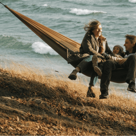 En familie på tre hygger i en hængekøje lige ud til havet på Fyn i Nyborg.