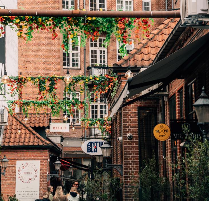 Et dekoreret stræde med skilte, røde facader og mennesker, der går