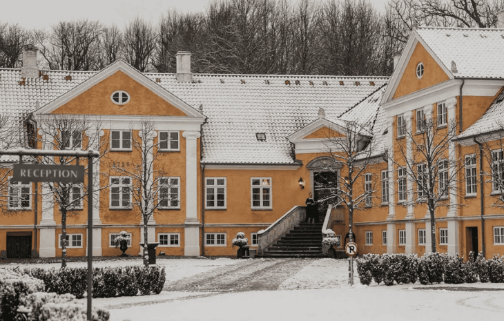 En gul to-længet herregård med sne