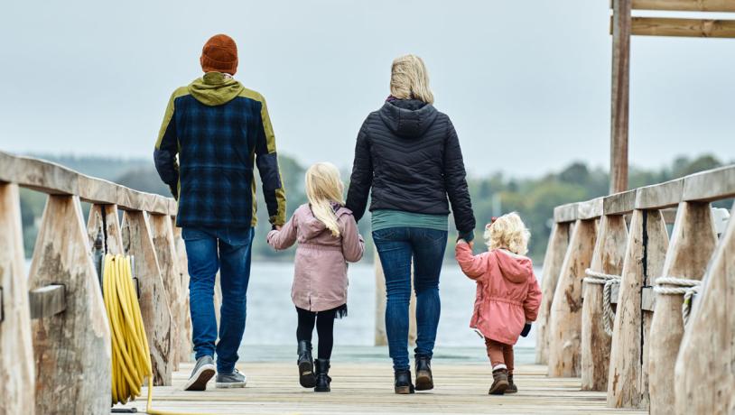 Familie på badebro i Troense på Tåsinge - to voksne og to børn går med ryggen til og holder i hånd