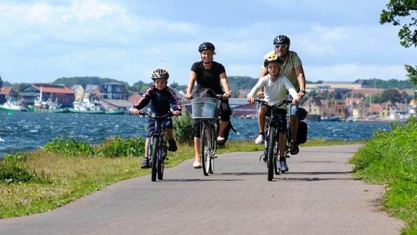 Familie på to voksne og to børn cykler langs kysten på Thurø.