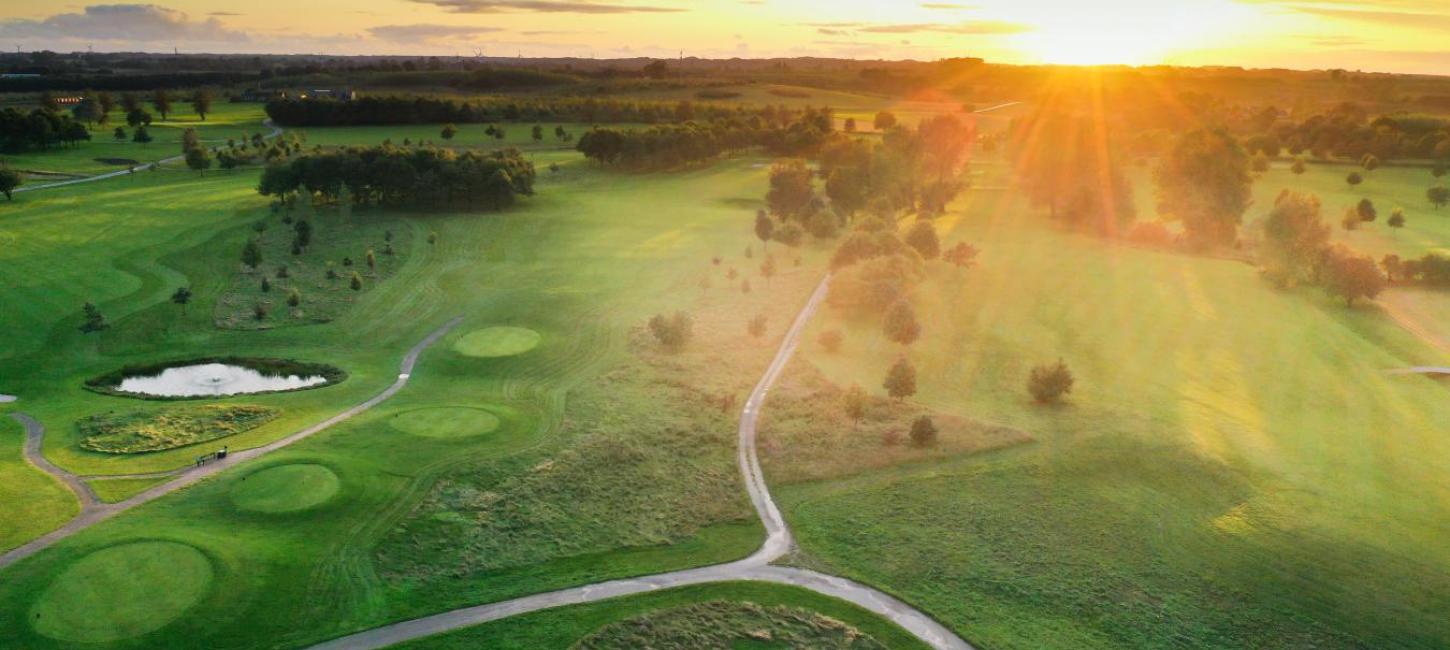 Odense Eventyr Golf set oppefra med solopgang i baggrunden