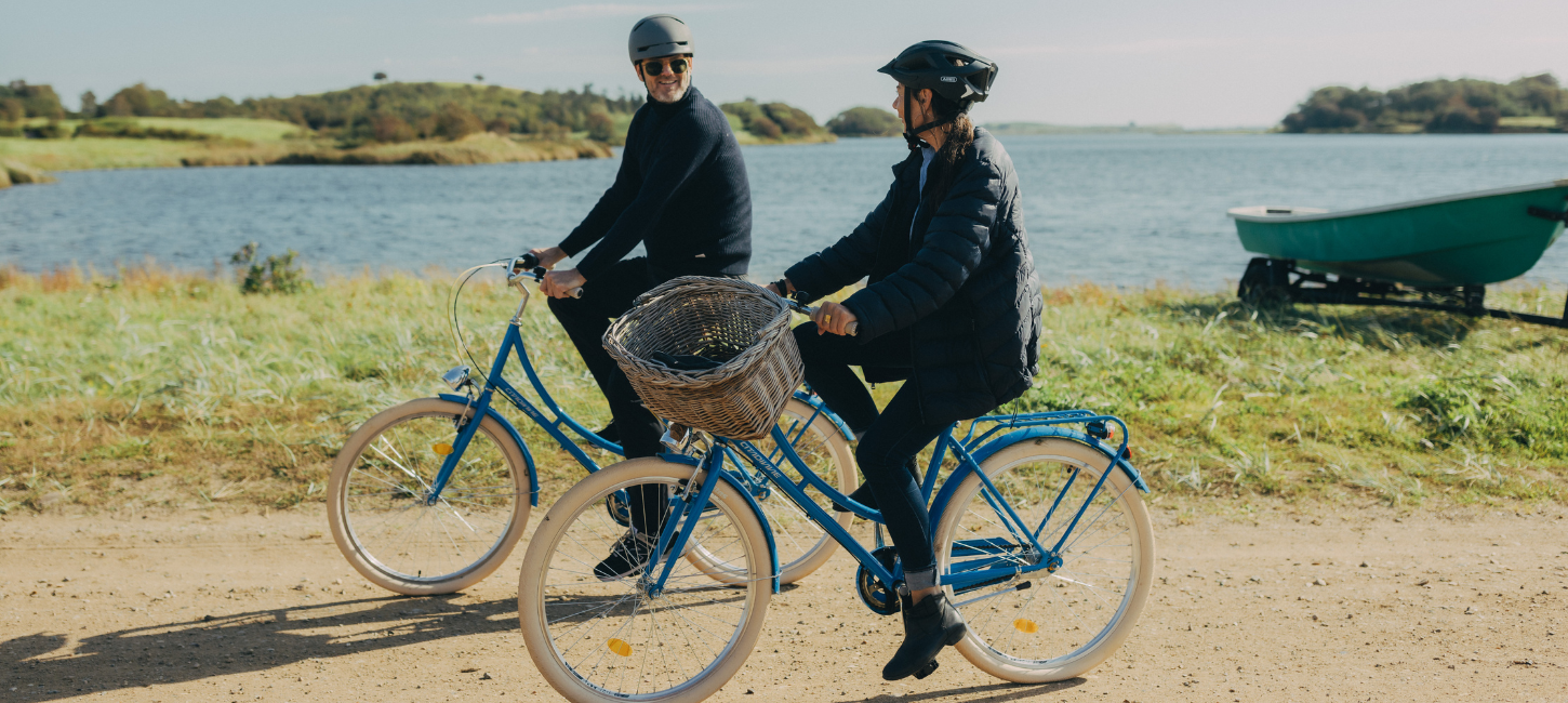 To cyklister på tur på grusvej med hav i baggrunden