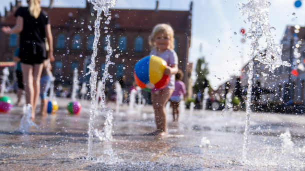Et barn hygger sig i en springvand omgivet af farverige bolde på Nyborg Torv.