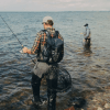 To lystfiskeri iklædt outdoortøj og waders står i havet med fiskestænger