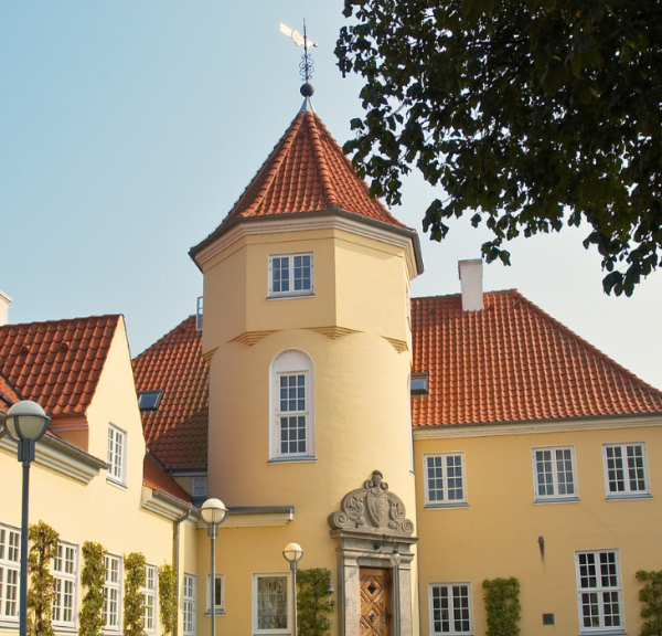 Et gult hotel med rødt tegltag og et tårn