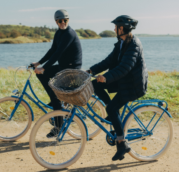 To cyklister på tur på grusvej med hav i baggrunden