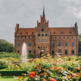 Egeskov Slot med rosenhave med blomstrende roser i forgrunden