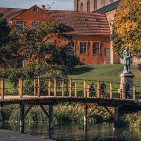 En bro over Odense Å med en skulptur af H. C. Andersen i baggrunden