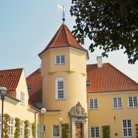 Et gult hotel med rødt tegltag og et tårn